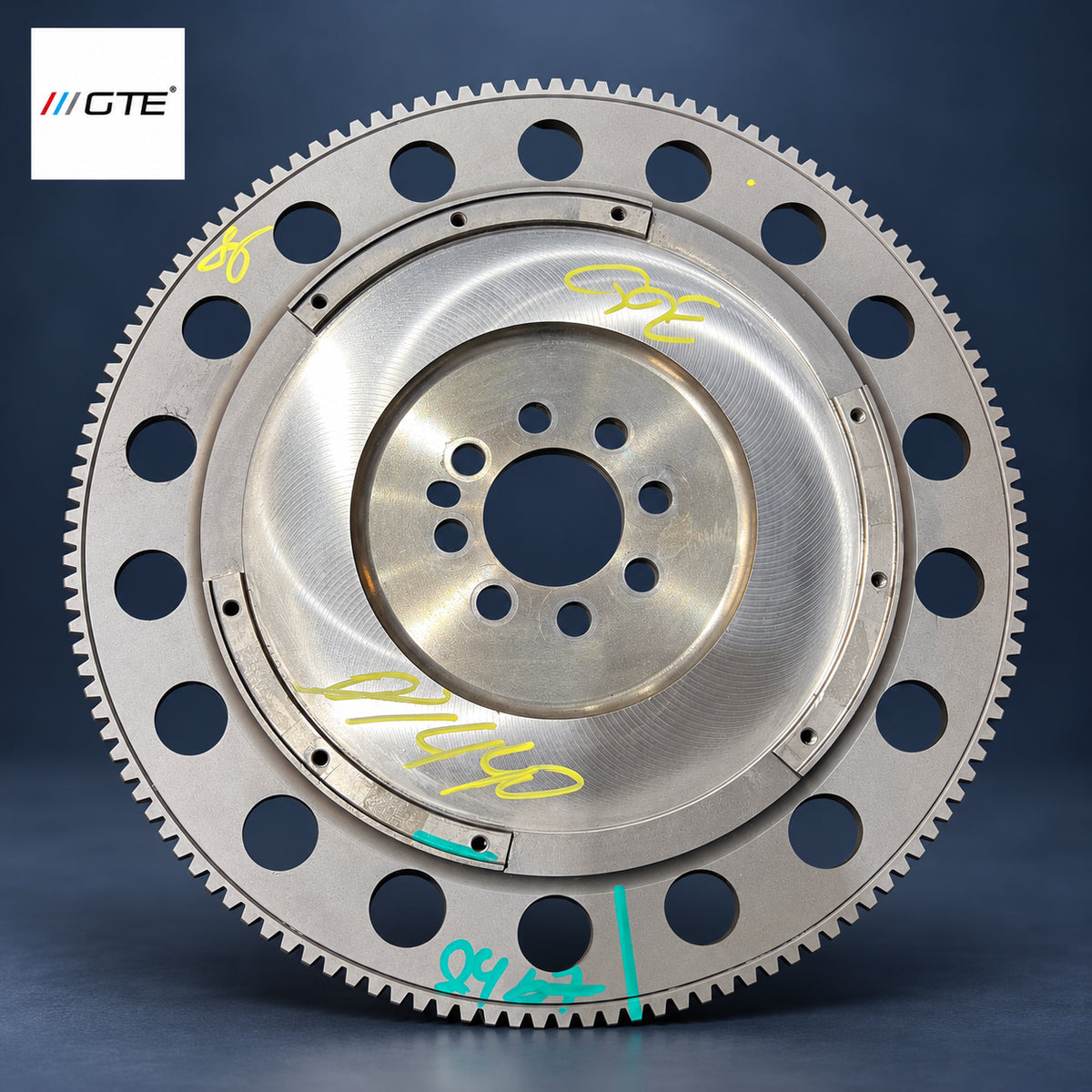 Aston Martin flywheel service example showing friction surface, ring gear and inspection marks; flywheel service is separate