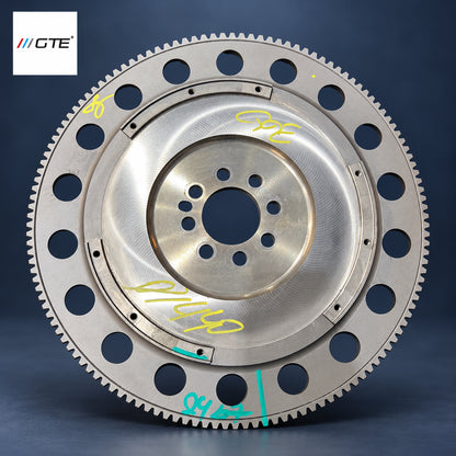 Aston Martin flywheel service example showing friction surface, ring gear and inspection marks; flywheel service is separate